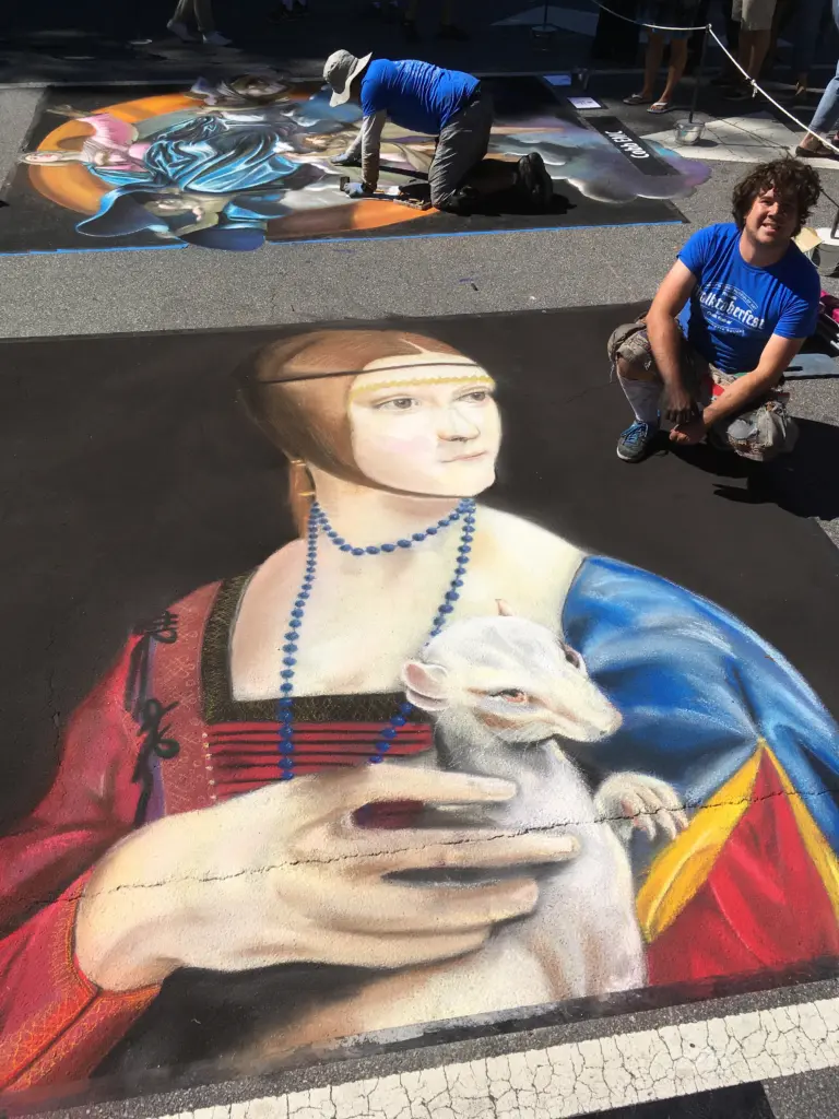 Chalk reproduction of Leonardo da Vinci's Lady with an Ermine on a street, with artists working on other pieces nearby.