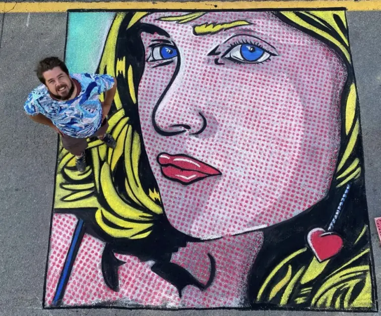Zach Herndon stands at the corner of his pop-art chalk portrait of a blonde woman with blue eyes, red lips and a small red heart, drawn in bold black outlines over pink Ben-Day dots.